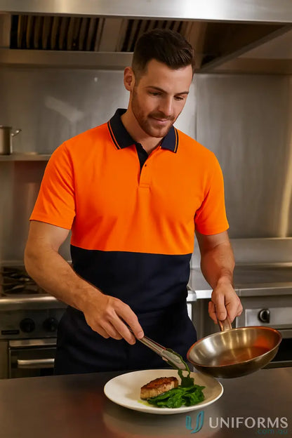 Male chef in HiVis Food Industry Pocketless Buttonless SS Polo plating food for food processing teams