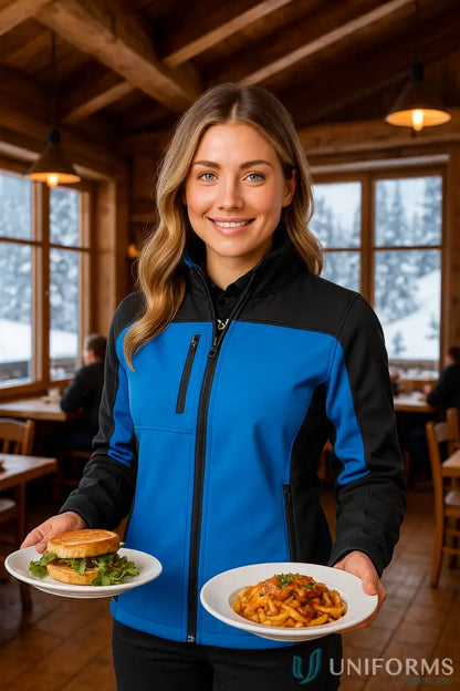 Woman in a blue and black Ladies Cascades Softshell holding plates of food, perfect for stay dry outdoor enthusiasts