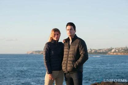 Two women wearing warm l7682 ladies puffer jackets by the sea, stay warm in style