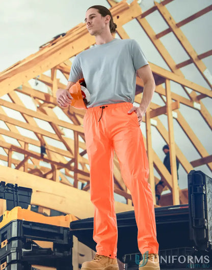 Construction worker in orange lightweight nylon waterproof rain pants for tough weather