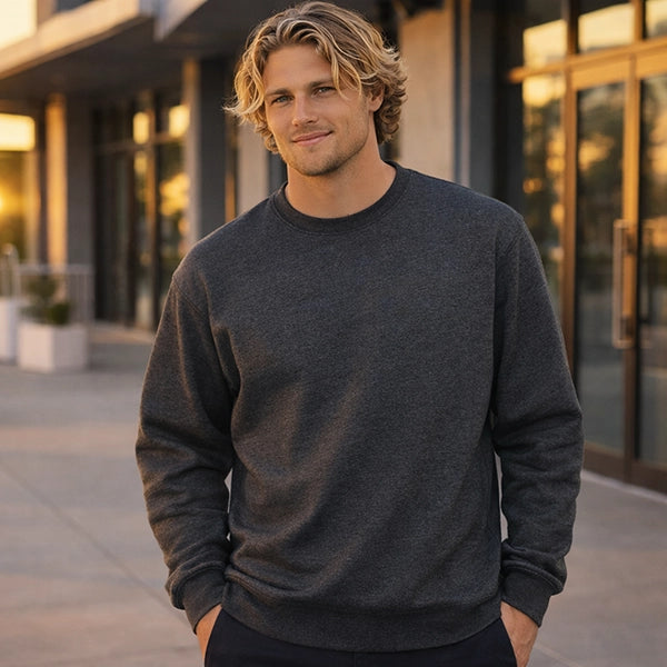 Man wearing a dark gray sweater standing outdoors with a blurred building background