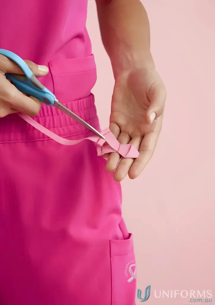 Pink ribbon being cut with scissors on NBCF Womens Pink V-Neck Scrub Pant, pink jogger scrub style