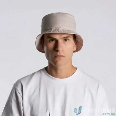 Man wearing a light beige bucket hat with reinforced brim and eyelets