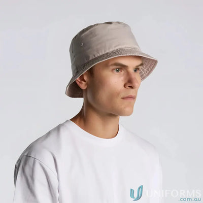 Man wearing a light beige bucket hat with reinforced brim and eyelets, lightweight style