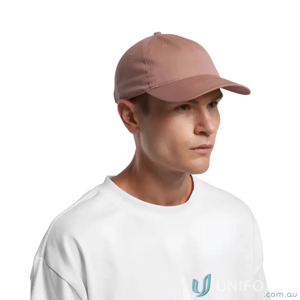 Person wearing a rose-colored baseball cap with adjustable metal clasp and white t-shirt
