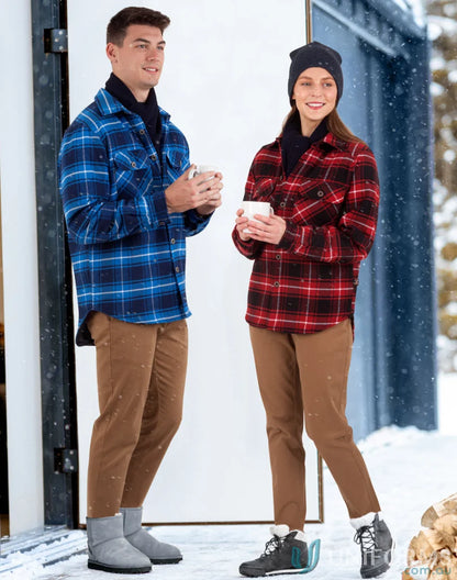 Two people in winter boots wearing stylish unisex quilted flannel shirt-style jackets in snow