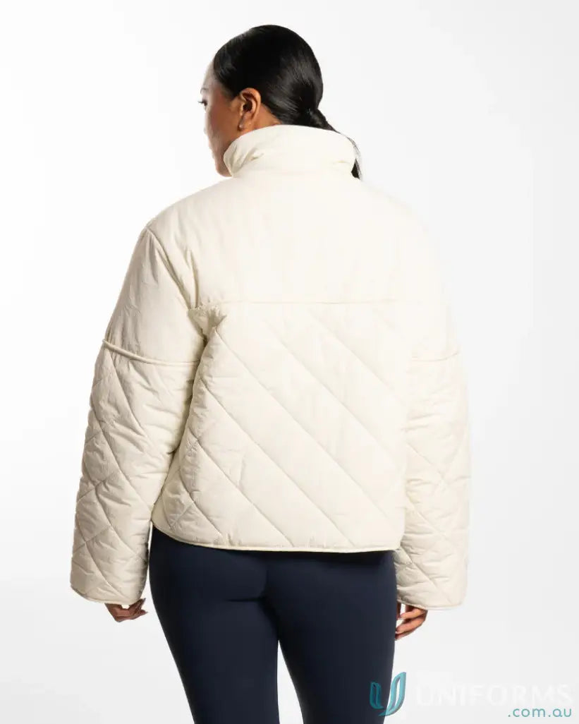 Cream-colored quilted puffer jacket with diagonal stitching and high collar ideal for workwear and uniforms