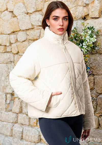 Cream-colored quilted puffer jacket with high collar and zip front perfect for workwear and uniforms