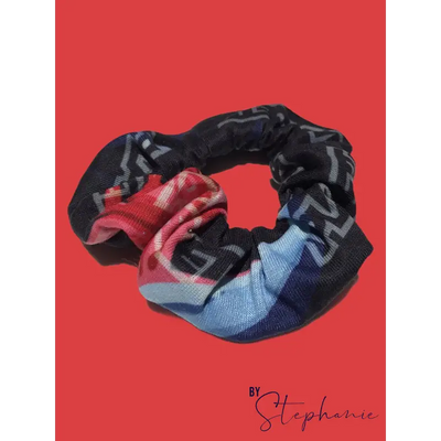 A black rainbow scrunchie with a colorful red blue and white plaid pattern perfect for workwear and uniforms