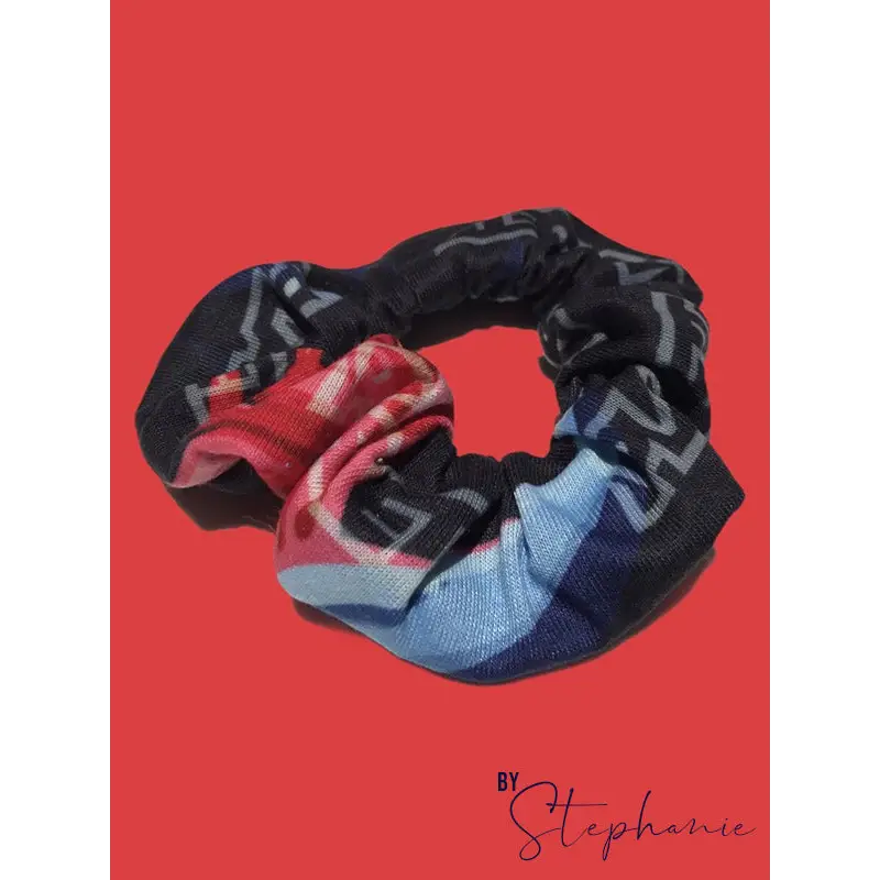 A black rainbow scrunchie with a colorful red blue and white plaid pattern perfect for workwear and uniforms