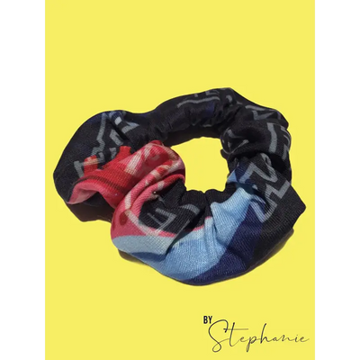 A black rainbow scrunchie with a bold red blue and gray geometric pattern perfect for workwear or uniforms