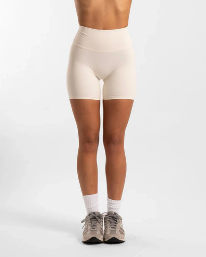 Beige high-waisted seamless invicible scrunch onyx shorts with white socks and gray sneakers