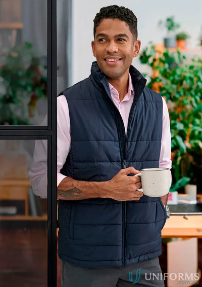 Man in navy blue sustainable insulated puffer vest made from recycled PET bottles holding a mug