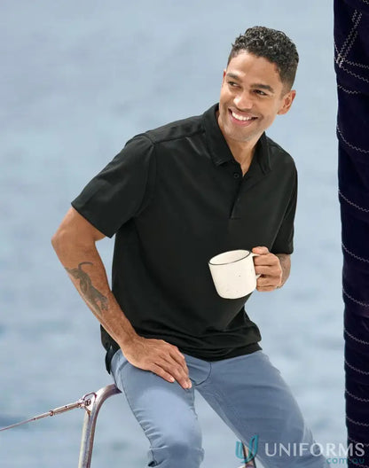 Man in black polo shirt holding mug showcasing the Sustainable Jacquard Knit Polo for corporate teams