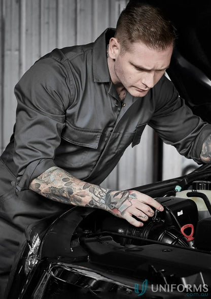 Tattooed mechanic wearing Syzmic Service Overall with hip pockets and pen partition