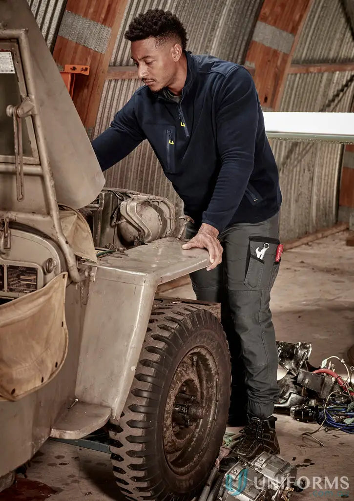 Man in workwear repairing vehicle wearing Syzmic Streetworx Heritage Cuffed Pant with triple-stitched crotch panel