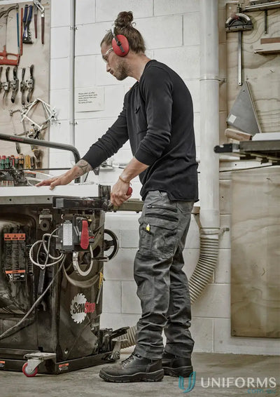 Man in streetworx heritage pant zp820 with safety gear using a saw for work