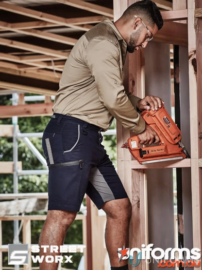 Man wearing Syzmic Streetworx Stretch Shorts with four-way stretch crotch using a nail gun