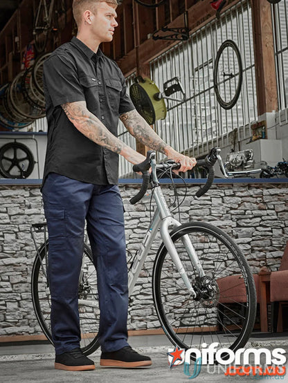 Man in black shirt and navy Syzmik Drill Cargo Pant with bicycle for all-day comfort