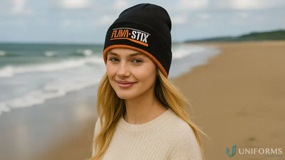Young woman wearing a black cable knit beanie with orange trim and light sweater