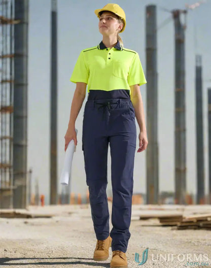 Woman in yellow hard hat and water repellent flexi work pants holding blueprint