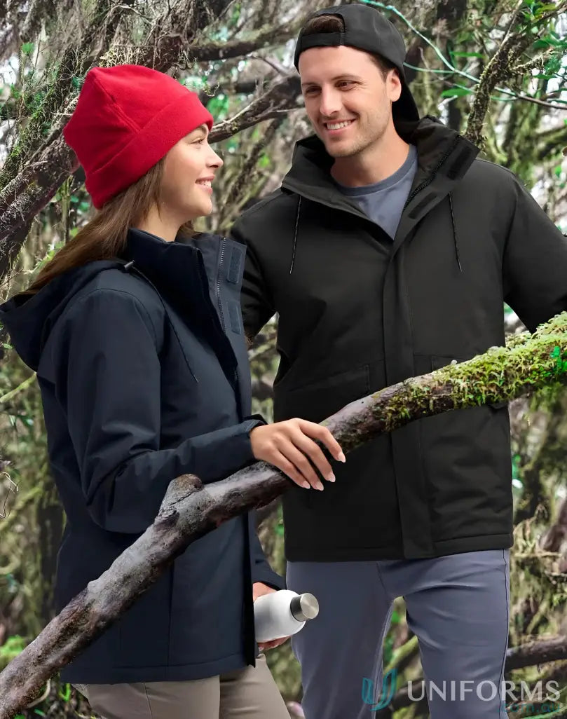 Two people in outdoor gear wearing Vic Metro Waterproof Quilted Jackets among mossy trees
