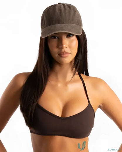 Woman wearing a vintage washed cap and bikini top, stylish vintage washed cap look