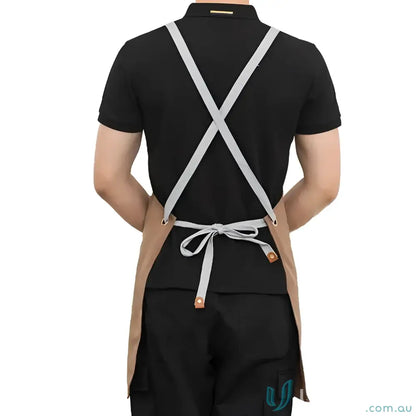 Person wearing brown waterproof canvas kitchen apron with gray straps and tied waist