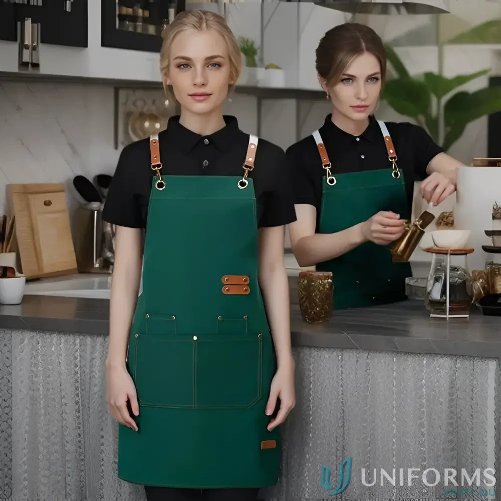 Two women in matching waterproof canvas kitchen aprons with brown leather straps