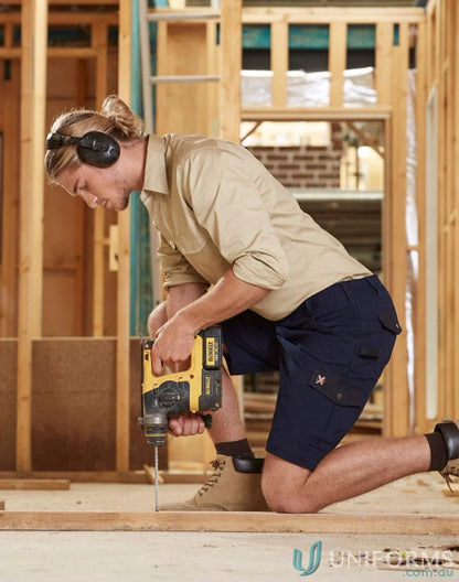 Man in XStreet Stretch Cargo Shorts using yellow power drill, showing stretch cargo work style