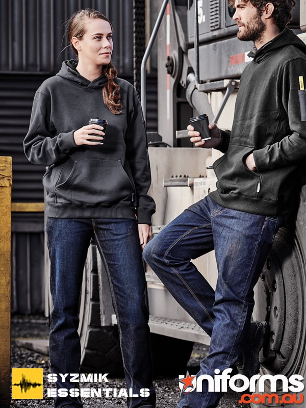 A couple stand talking while drinking coffee showcasing the Syzmik Stretch Denim Work Jean.