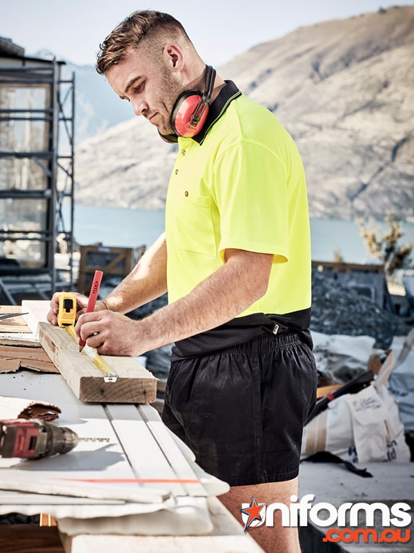 A man in a yellow polo works on a piece of wood, showcasing the Syzmic brand Men's Rugby Shorts ZS105.
