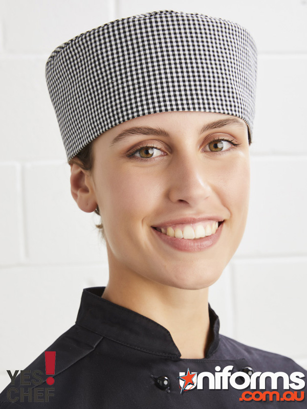 A smiling woman dons a Biz Collection Chef Cap CH238, embodying the spirit of a dedicated and joyful chef.