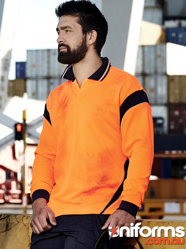 A man in an orange Syzmik Hi Vis Aztec Long Sleeve Polo ZH249 showcasing a casual work look.