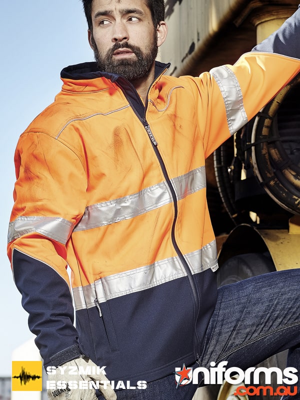A man standing by a truck wearing the Syzmic Unisex Hi Vis Softshell Jacket ZJ353.