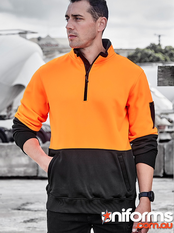 A man wearing a Syzmic brand orange and black sweatshirt, showcasing the Unisex Hi Vis 1/2 Zip Pullover ZT476 design.