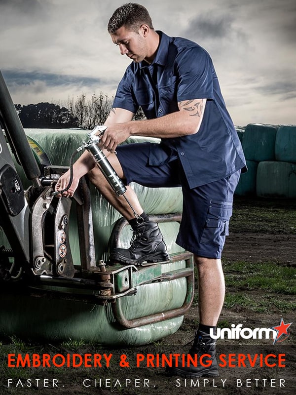 syzmik-workwear-zw1213.jpg_product_product A man in a blue shirt and blue jeans on a tractor, wearing Lightweight Tradie shirt ZW120.